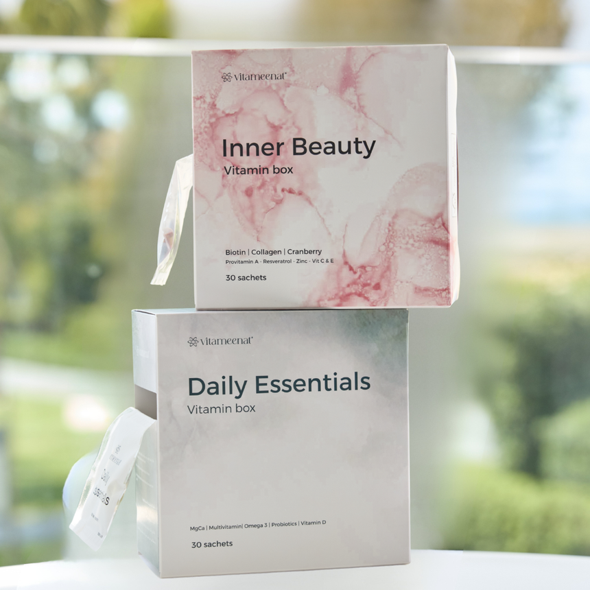 Two vitamin box packaging with 'Inner Beauty' and 'Daily Essentials' on a blurred natural background