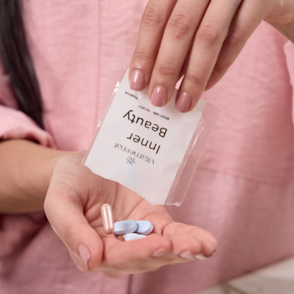 Person holding a clear sachet labeled 'Inner Beauty' with supplements and vitamin tablets and capsules